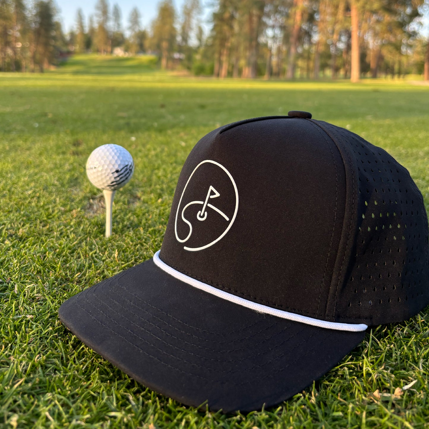 Black cap with a white DFB Day One logo on a grassy golf course